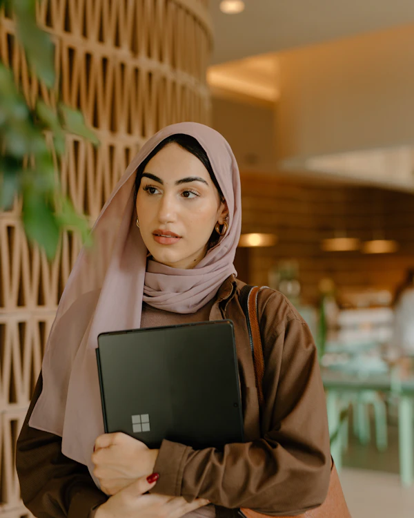 Young woman founder holding a laptop in a café